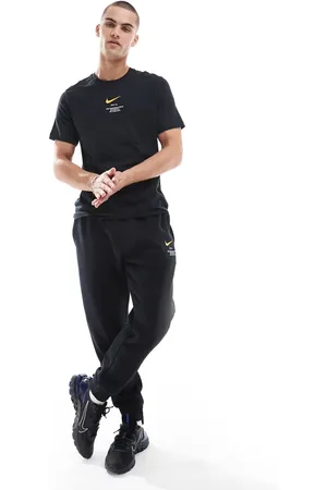 Nike Joggers negros y amarillos con estampado gráfico del logo Swoosh de Club