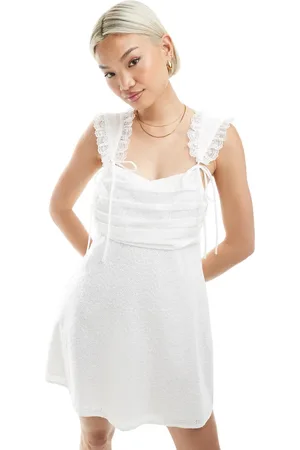 The Frolic Vestido corto blanco con pecho fruncido, detalle de lazos y ribete de encaje exclusivo de